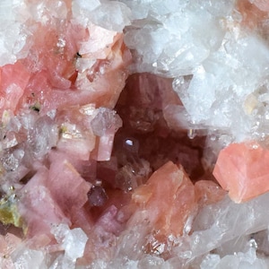 Puede incluir: Un primer plano de un cúmulo de cristales rosa y blanco. Los cristales están dispuestos en un patrón aleatorio y tienen una variedad de formas y tamaños. Los cristales son translúcidos y tienen un ligero brillo.