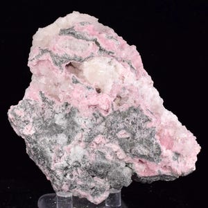May include: A mineral specimen with a rough, irregular shape, showcasing a mix of pink, grey, and white colours. The surface has a varied texture, with crystalline areas and darker, more solid sections. The overall appearance is natural and unpolished.