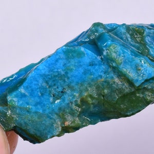 Może przedstawiać: Surowy, nieregularny kawałek turkusu o żywym niebiesko-zielonym wzorze.