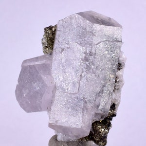 May include: A cluster of clear, translucent, and slightly pink calcite crystals with a metallic, gold-colored pyrite crystal attached. The crystals are sharp and well-defined, with a glassy luster.