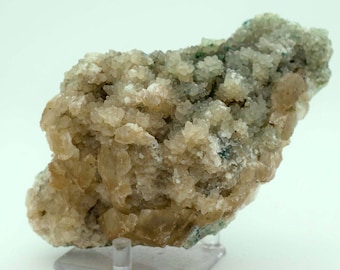 Op de afbeelding: Een cluster van lichtbruine en witte kristallen met een groene mineraalmatrix. De kristallen zijn in een ruwe, natuurlijke formatie geclusterd.