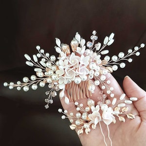 May include: A set of two gold hair combs with white pearl and pink flower accents. The larger comb has a comb base and the smaller comb has two bobby pins.