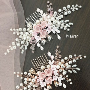 May include: Two bridal hair combs featuring pink flowers, pearls and crystals. The comb on the left is silver, and the comb on the right is rose gold.