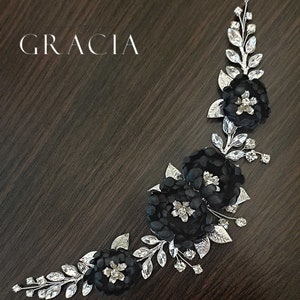 May include: Black floral hair comb with silver leaves and rhinestones. The comb is curved and has three black fabric flowers.