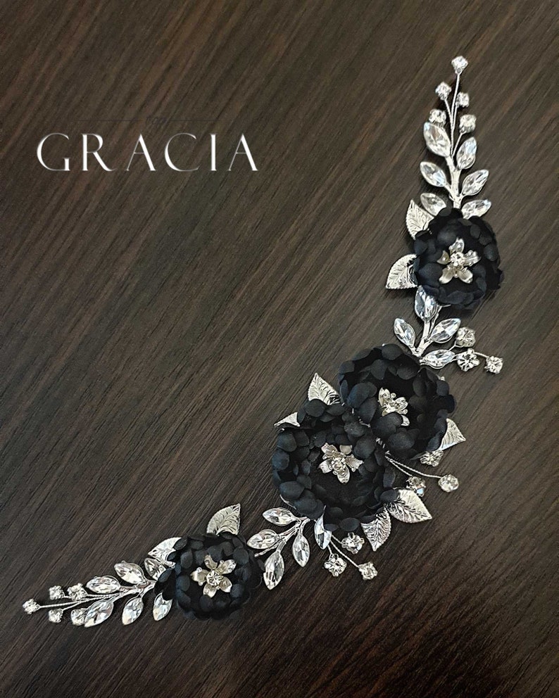 May include: Black floral hair comb with silver leaves and rhinestones. The comb is curved and has three black fabric flowers.