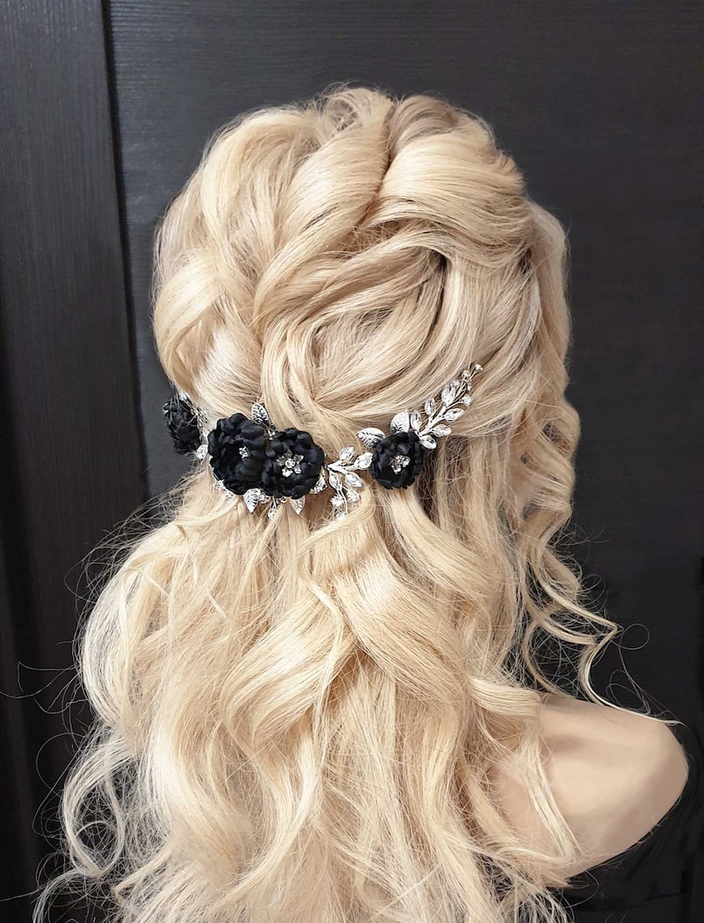 May include: A silver hair comb with black fabric flowers and rhinestones. The comb is worn in a woman's blonde hair.