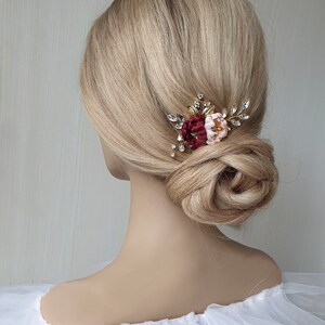 May include: A gold hair comb with burgundy and pink fabric flowers and rhinestones.