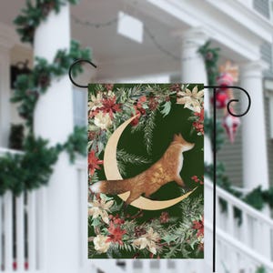 Peut inclure: Un drapeau de jardin décoratif avec un renard sautant au-dessus d'un croissant de lune. Le motif comprend un fond vert foncé avec des accents floraux et de baies. Le drapeau est affiché sur un support en métal noir.