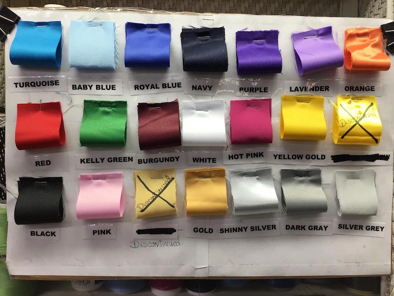 May include: A color chart with 18 different fabric swatches. The swatches are labeled with the following colors: turquoise, baby blue, royal blue, navy, purple, lavender, orange, red, kelly green, burgundy, white, hot pink, yellow gold, black, pink, gold, shiny silver, dark gray, and silver gray.