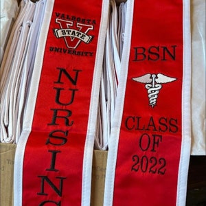 May include: Red and white graduation sash with the Valdosta State University logo, the words "Nursing" and "BSN", a caduceus symbol, and the text "Class of 2022".