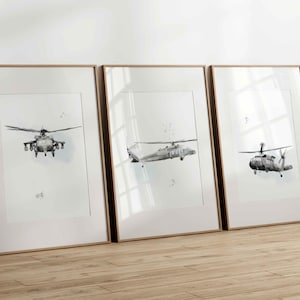 Peut inclure: Trois cadres muraux verticaux contenant des illustrations en noir et blanc d'hélicoptères militaires. Chaque impression présente un angle différent de l'appareil sur un fond blanc, encadré par du bois clair avec un passe-partout blanc.