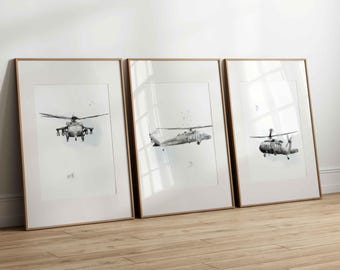 May include: Three framed vertical wall art prints featuring black and white illustrations of military helicopters. Each print displays a different angle of the aircraft against a plain white background, housed in light wood frames with white matting.