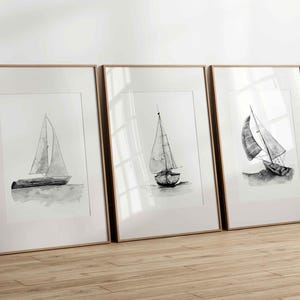 May include: Three framed black and white illustrations of sailboats on a white background. The frames are light wood.