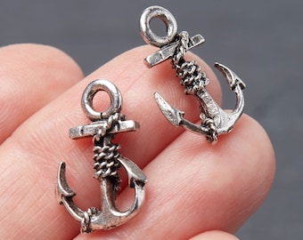 May include: Two small, silver-colored anchor charms. Each anchor has a detailed design with a rope wrapped around the shank. The anchors are displayed against a neutral background.