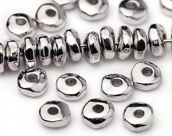 May include: Silver-colored, irregular-shaped beads. Some are strung on a wire, while others are scattered. The beads have a shiny, metallic finish and a hole through the center, suitable for jewelry making or crafts.