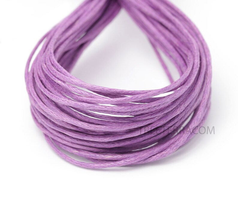 May include: A bundle of lavender-colored waxed cotton cord, tightly coiled. The cord appears smooth and uniform in color, suitable for various crafting projects. The background is plain white, highlighting the cord's color and texture.