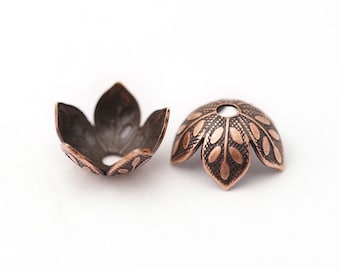 May include: Two antique copper-colored bead caps, shaped like stylized flower petals. The caps have a detailed, embossed design and a small hole at the center. The caps are ideal for jewelry making and crafting.