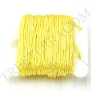 Puede incluir: Un carrete de cord&oacute;n amarillo brillante, bien enrollado. El cord&oacute;n es de un color amarillo vibrante y soleado, y est&aacute; enrollado en un soporte de pl&aacute;stico blanco. La imagen est&aacute; tomada sobre un fondo blanco.