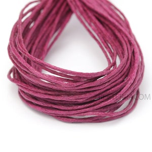 May include: Close-up of a bundle of magenta-colored waxed cotton cord. The cord is tightly wound, showing multiple strands. The texture appears smooth and slightly shiny, suitable for various crafting projects.