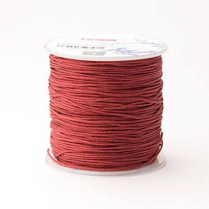 Puede incluir: Un carrete de cord&oacute;n rojo oscuro, bien enrollado y listo para manualidades. El cord&oacute;n es de un color s&oacute;lido y rico, y el carrete tiene una base de pl&aacute;stico transparente y una parte superior blanca con detalles impresos. Ideal para hacer joyas, macram&eacute; u otros proyectos de bricolaje.