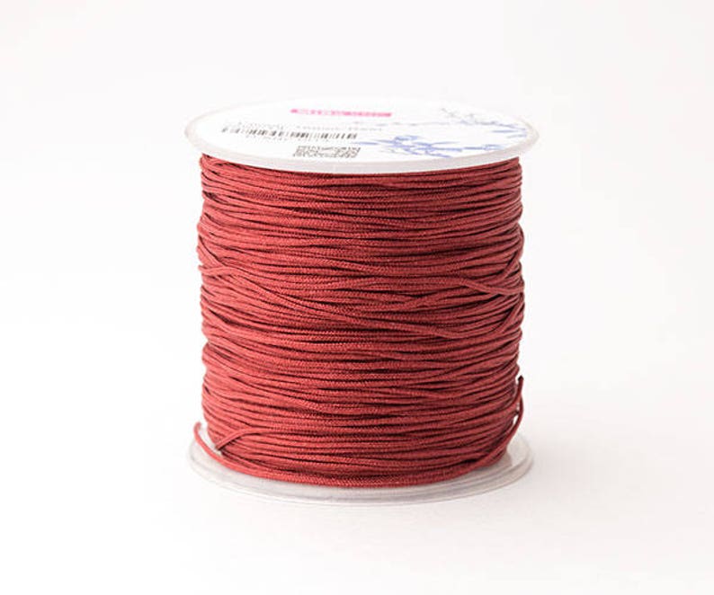Puede incluir: Un carrete de cord&oacute;n rojo oscuro, bien enrollado y listo para manualidades. El cord&oacute;n es de un color s&oacute;lido y rico, y el carrete tiene una base de pl&aacute;stico transparente y una parte superior blanca con detalles impresos. Ideal para hacer joyas, macram&eacute; u otros proyectos de bricolaje.