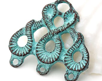 May include: A turquoise-colored metal decorative component with an openwork design. The component has a distressed finish with dark brown accents and several circular openings. It has a unique, ornate shape with multiple attachment points.