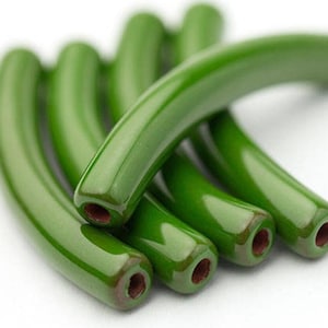 May include: Close-up of several curved, glossy green beads. Each bead has a smooth, rounded shape with a hole at each end. The beads are piled together, showcasing their vibrant color and reflective surface.