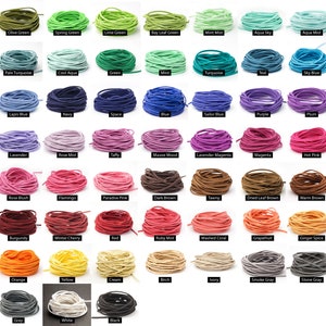 Può includere: Una collezione di cordoncini in camoscio colorati in varie tonalità, tra cui verde, blu, rosa, marrone e grigio. Ogni cordoncino è ordinatamente arrotolato ed etichettato con il suo nome di colore, come "Olive Green", "Navy" e "Hot Pink".