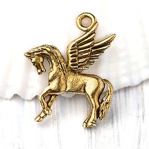 Op de afbeelding: Een goudkleurige Pegasus-bedel met gedetailleerde vleugels en een lus om aan sieraden of andere knutselwerken te bevestigen. Het mythische gevleugelde paard wordt in een dynamische pose afgebeeld, waarbij de elegante vorm wordt getoond.