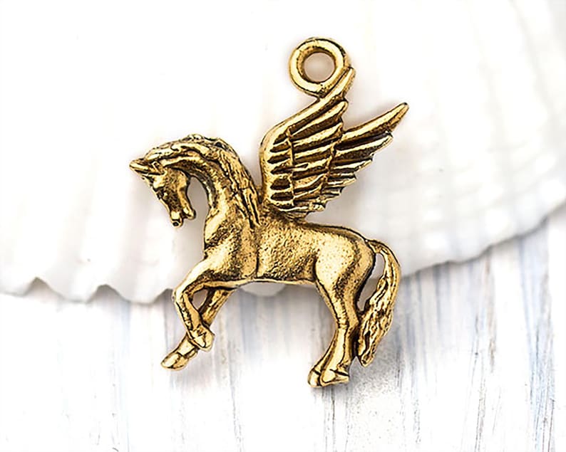 Op de afbeelding: Een goudkleurige Pegasus-bedel met gedetailleerde vleugels en een lus om aan sieraden of andere knutselwerken te bevestigen. Het mythische gevleugelde paard wordt in een dynamische pose afgebeeld, waarbij de elegante vorm wordt getoond.