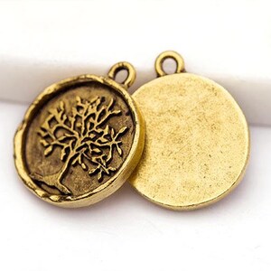 May include: Two antique gold-colored round pendants. One pendant features a detailed tree design, while the other has a plain surface. Both pendants have a small loop at the top for attaching to a chain or other jewelry.