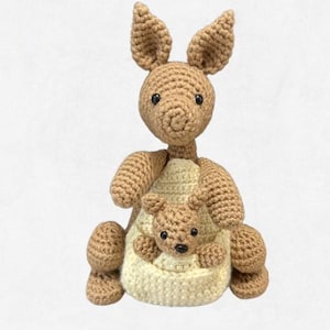 May include: A crochet pattern featuring a vintage Kanga and Roo design. The image shows a crocheted kangaroo with a baby kangaroo in its pouch. The text reads "Vintage Kanga and Roo Crochet Pattern" and "Geeky Little Stitches".