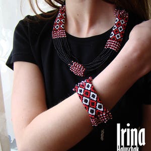 May include: A black beaded necklace and bracelet set with red and white geometric patterns. The necklace is multi-layered and the bracelet is a single band.