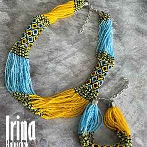 May include: A yellow and blue beaded necklace and bracelet set with a geometric pattern. The necklace has a silver clasp and the bracelet has a silver toggle clasp.