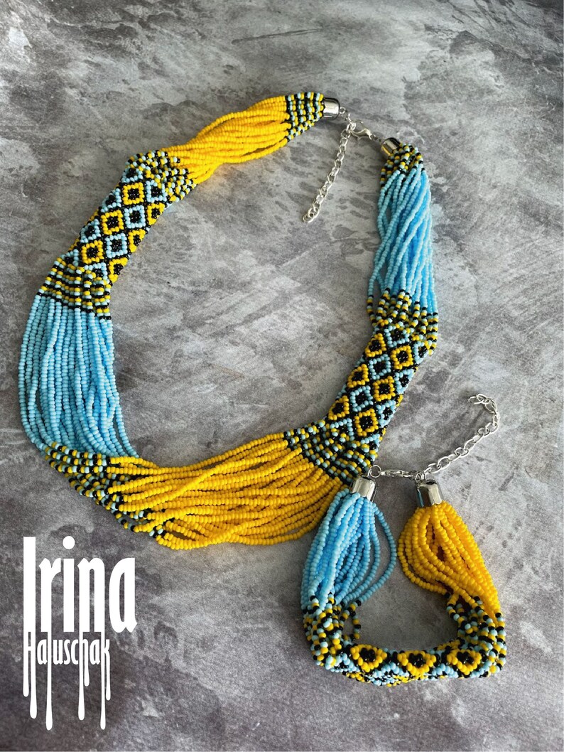 May include: A yellow and blue beaded necklace and bracelet set with a geometric pattern. The necklace has a silver clasp and the bracelet has a silver toggle clasp.
