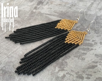 Pode incluir: Brincos de franjas de contas pretas e douradas com ganchos de prata. A parte superior dos brincos é dourada, passando para franjas pretas. Os brincos são feitos à mão e apresentam um design único.