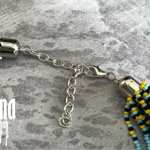 May include: A beaded necklace with a silver clasp. The beads are black, yellow, and light blue.