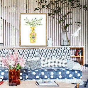 May include: A watercolor painting of a yellow and green vase with a bouquet of green leaves. The painting is framed in a gold frame and is hanging on a wall with wood paneling.