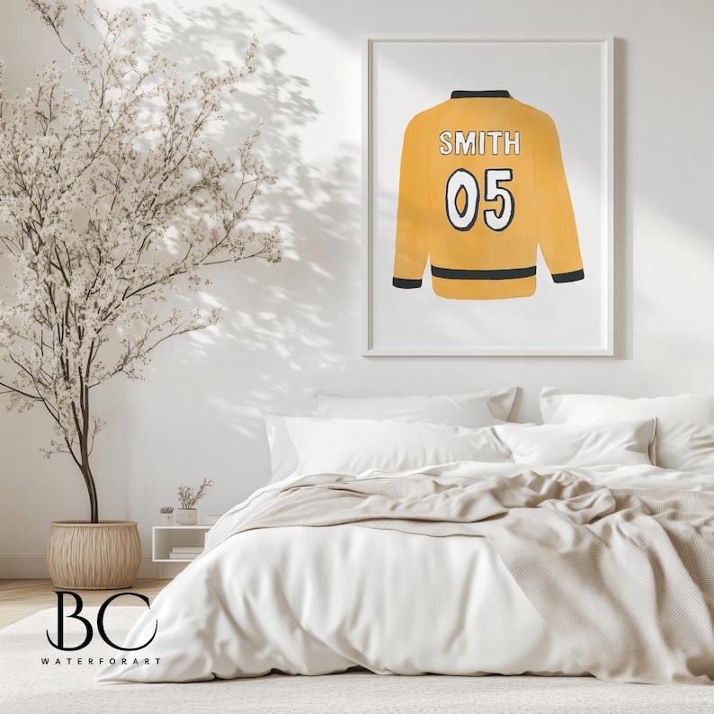 Pu&ograve; includere: Una stampa incorniciata bianca di una maglia gialla e nera con il nome "SMITH" e il numero "05" sul retro. La maglia &egrave; appesa a una parete bianca in una camera da letto.