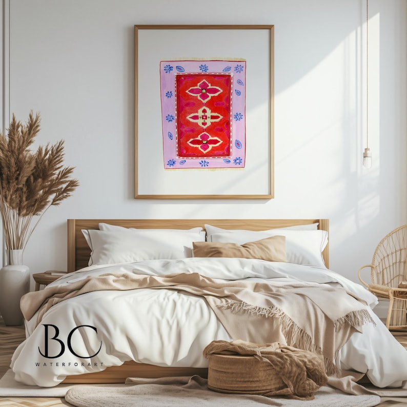 May include: A watercolor painting of a pink and red rug with a floral design. The painting is framed and hanging on a white wall above a bed with white bedding and a tan throw blanket.