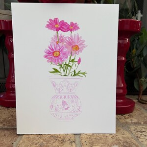 May include: A watercolor painting of a bouquet of pink daisies in a pink and white patterned vase.