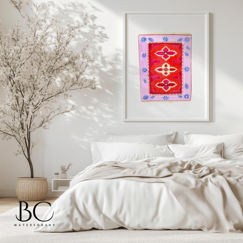 May include: A framed watercolor painting of a red rug with a floral pattern. The rug is surrounded by a pink border with blue and white accents. The painting is hanging on a white wall above a white bed with a beige blanket.