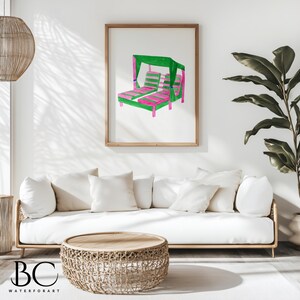 May include: A white sofa with pillows sits in front of a framed illustration of a pink and green striped lounge chair with a green canopy. A woven wicker coffee table sits in front of the sofa.