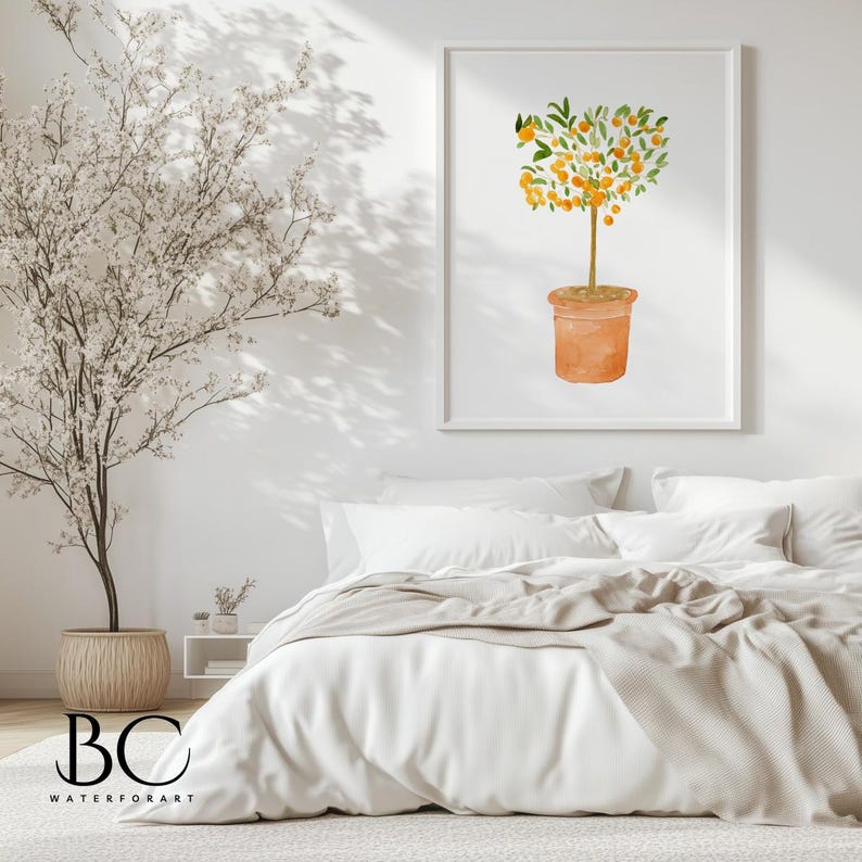 May include: A watercolor painting of a small orange tree with a terracotta pot. The tree is in a white frame and is hanging on a white wall above a white bed with a beige throw blanket.