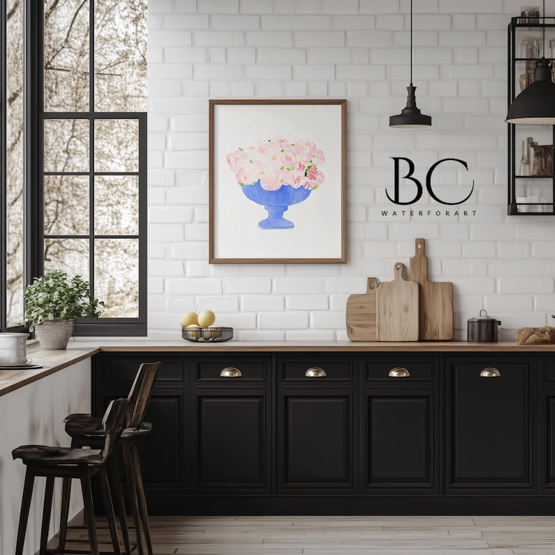May include: A watercolour painting of a blue vase filled with pink flowers. The painting is framed and hanging on a white brick wall in a kitchen setting. The text "BC WATERFORART" is visible below the painting.