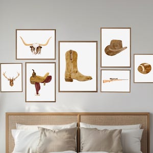 May include: A set of nine watercolor prints featuring western themes, including a cowboy hat, a saddle, a deer head, a longhorn skull, a pair of cowboy boots, a rifle, and a football. The prints are arranged in a grid pattern on a white wall above a wooden headboard.