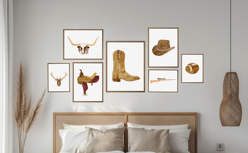 May include: A set of nine watercolor prints featuring western themes, including a cowboy hat, a saddle, a deer head, a longhorn skull, a pair of cowboy boots, a rifle, and a football. The prints are arranged in a grid pattern on a white wall above a wooden headboard.