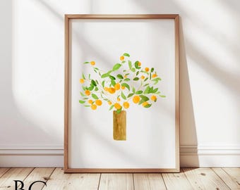 Op de afbeelding: Aquarel schilderij van een sinaasappelboom in een vaas, omlijst in een lichtbruine houten lijst. Het kunstwerk toont een vaas met een lichtbruine kleur, groene bladeren en oranje vruchten. Het kunstwerk wordt tentoongesteld op een houten vloer.
