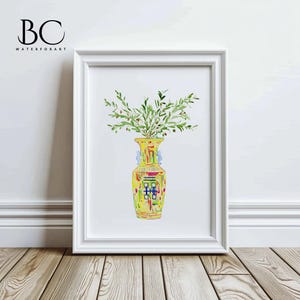 May include: A watercolor painting of a yellow vase with a colorful geometric pattern, filled with green olive branches. The vase is in a white frame against a white wall.