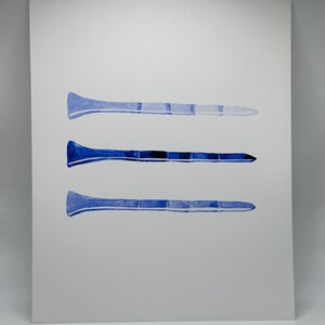 May include: Three watercolor paintings of blue golf tees on a white background.